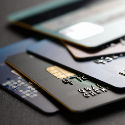 Pile of overlapping credit cards with visible magnetic stripes and chip readers, in shallow focus, suggesting financial transactions.
