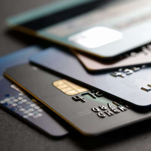 Pile of overlapping credit cards with visible magnetic stripes and chip readers, in shallow focus, suggesting financial transactions.